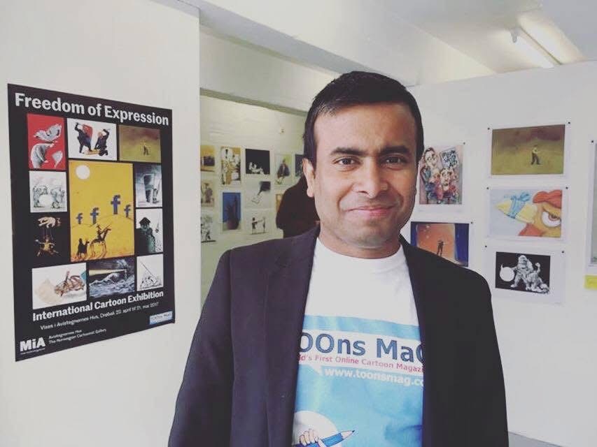 ARiF standing beside the Freedom of Expression International Cartoon Exhibition poster and displayed cartoons