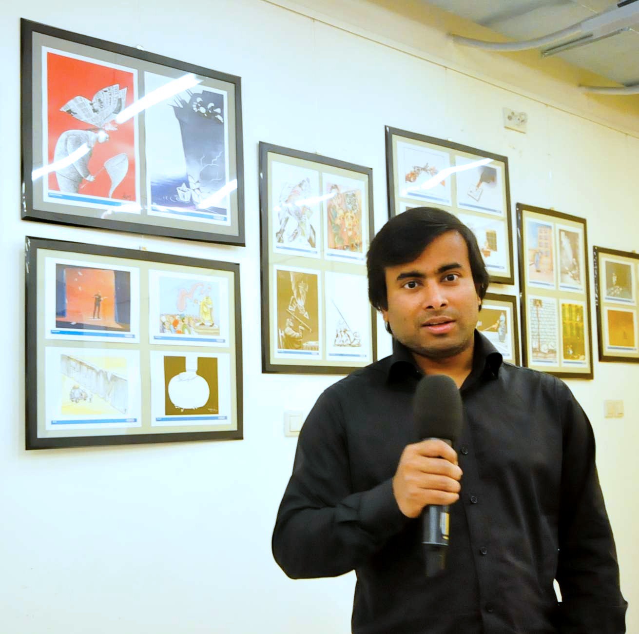 ARiF speaking at the opening of a Women's Rights cartoon exhibition, surrounded by framed cartoons